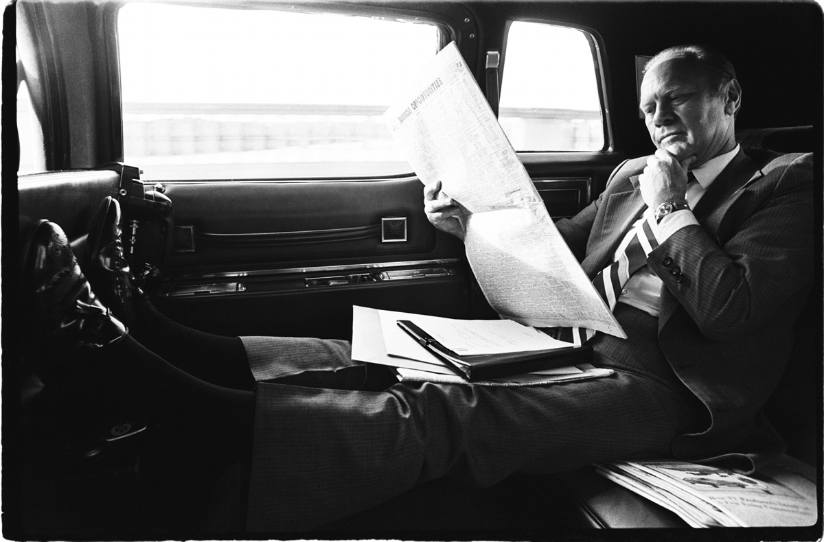 President Gerald R. Ford reading newspaper in car by David Hume Kennerly