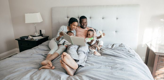 baby toddler and parents reading on bed Grand Rapids Baby and Beyond