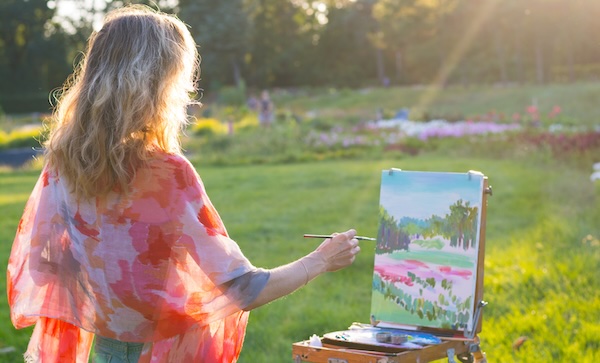 The painter paints oil paintings in the garden at sunset